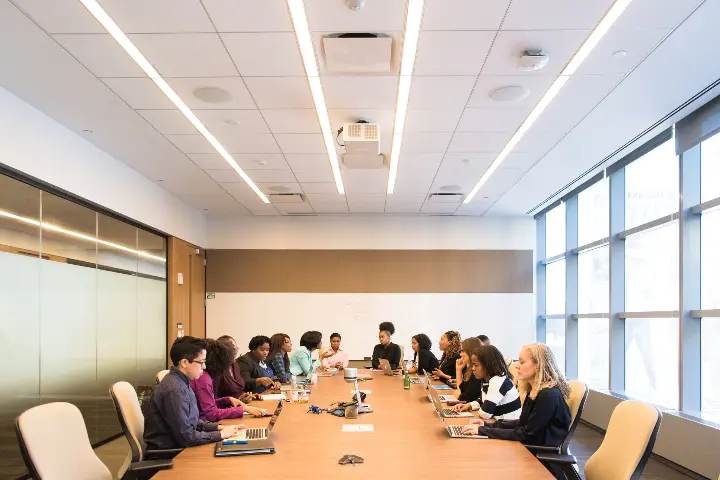 A diverse group of people in a meeting. They appear friendly and open to others’ ideas.