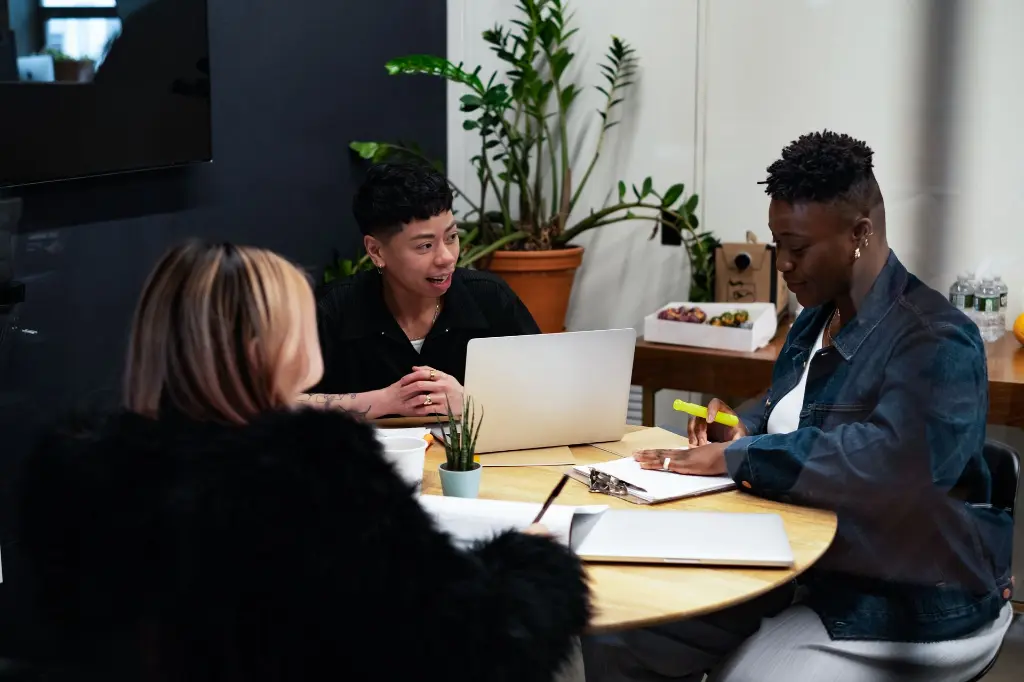 A group of co-workers of varying genders having a meeting, looking happy and fulfilled.